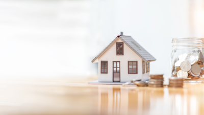 house next to a jar of coins to help visually demonstrate Loan Level Price Adjustment LLPA